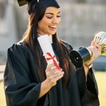 Graduation, student or woman with trophy or diploma outdoor for degree ceremony, achievement and excited. College graduate, person and scholarship success with academic milestone or certificate event.